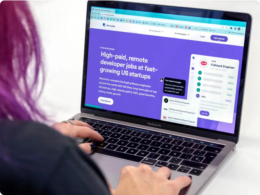 A laptop opened on a white table with Remotely.works website.